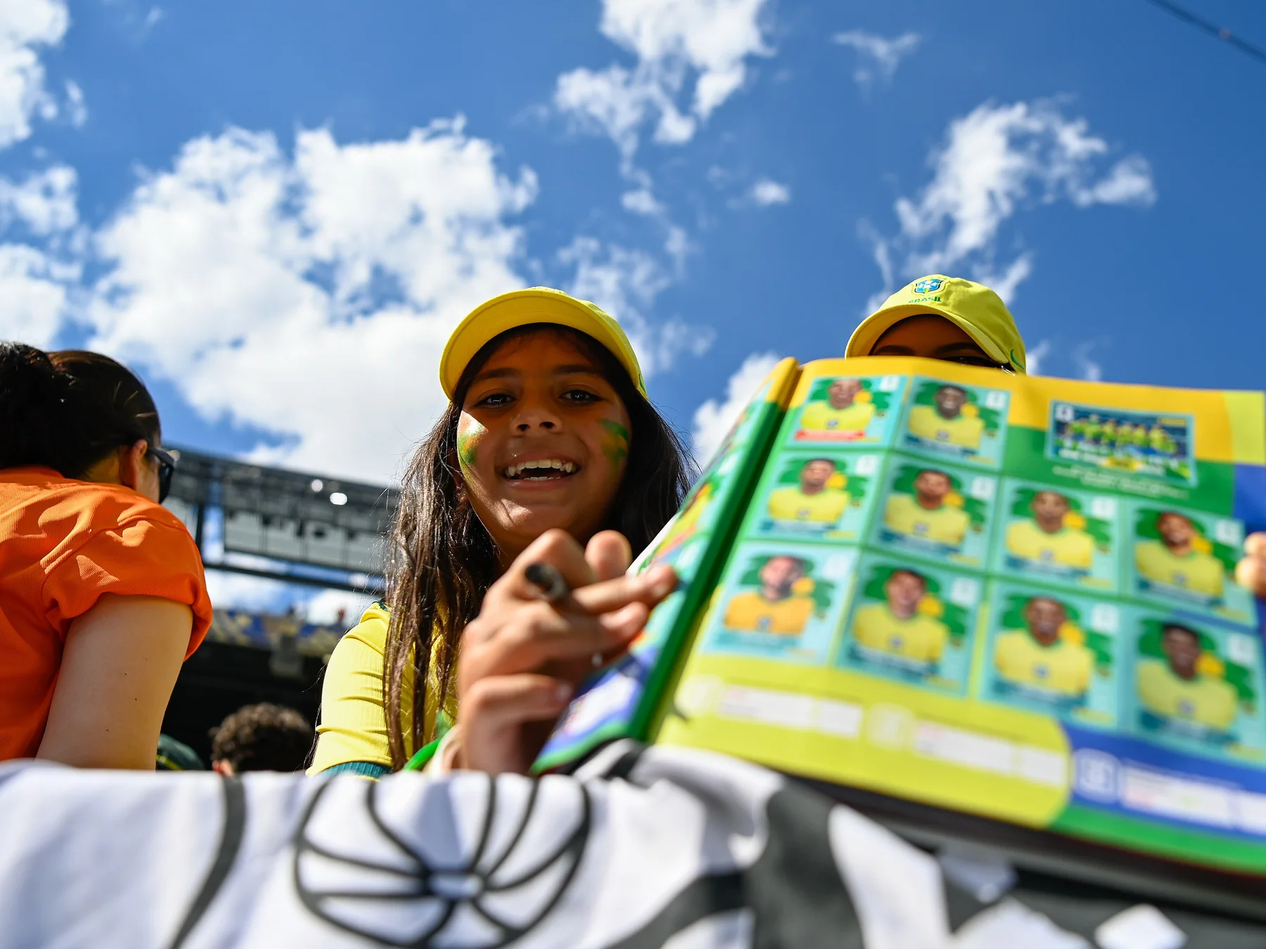 Smiling FIFA World Cup fans holding a football sticker album