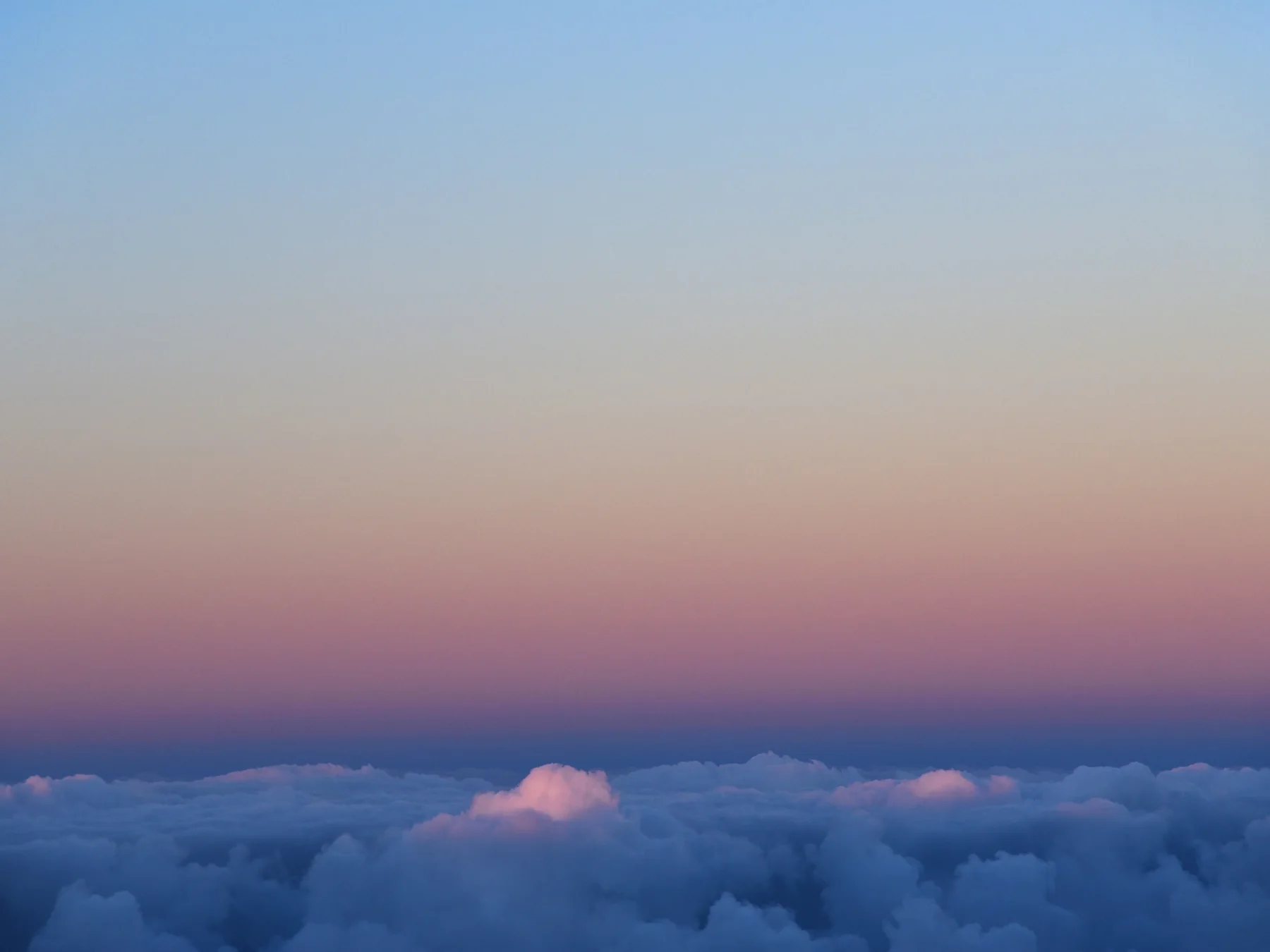 Pastel twilight sky above a broad sea of clouds