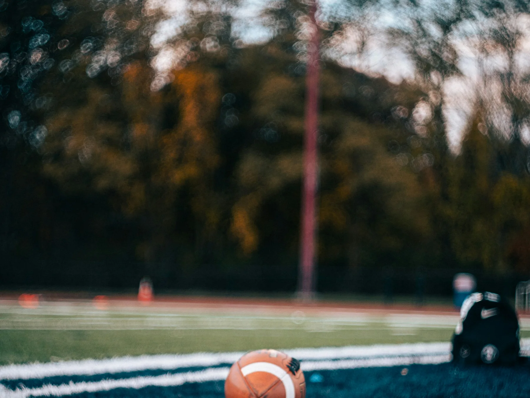American football resting on painted end zone turf before a game