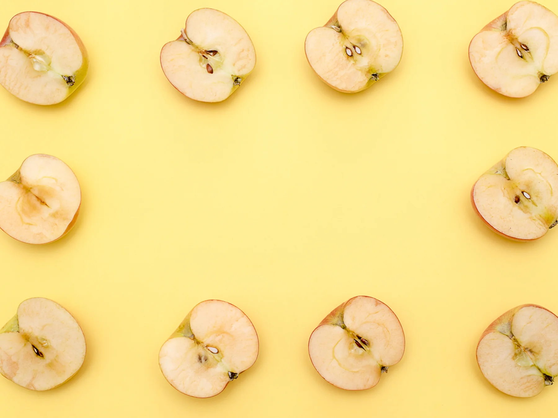 Apple halves arranged in a pattern on a bright yellow background
