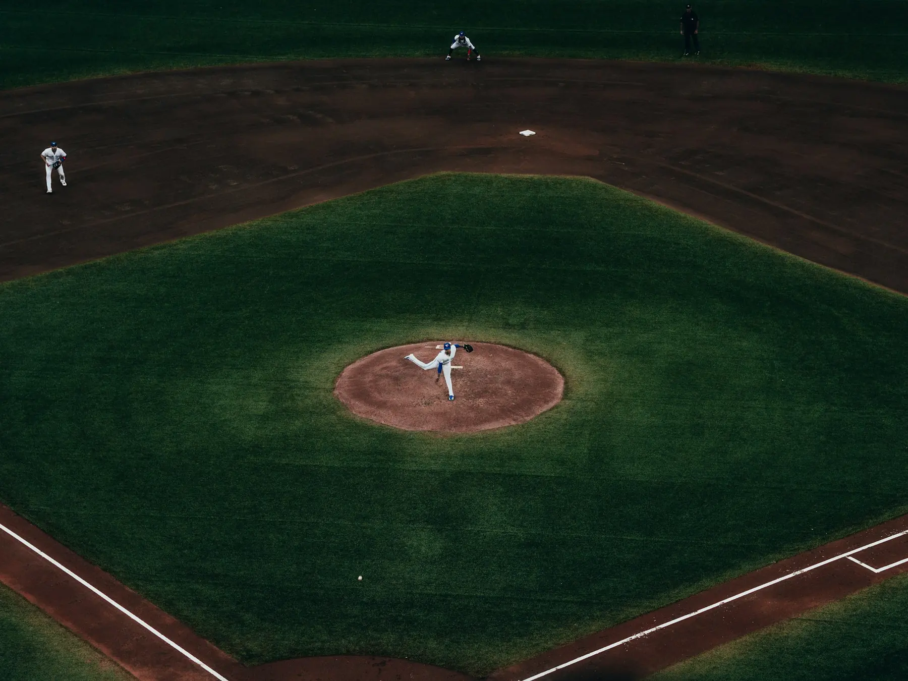 Baseball pitcher delivering a pitch from the center of the diamond