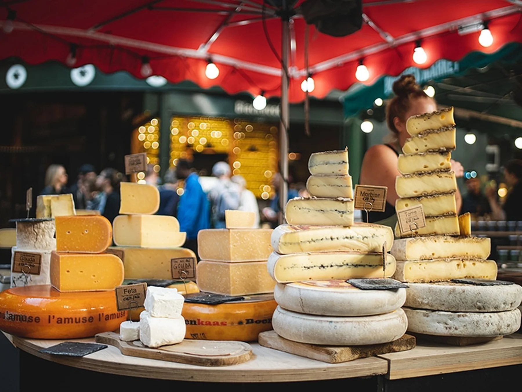 Cheese wheels and wedges displayed at a busy market stall