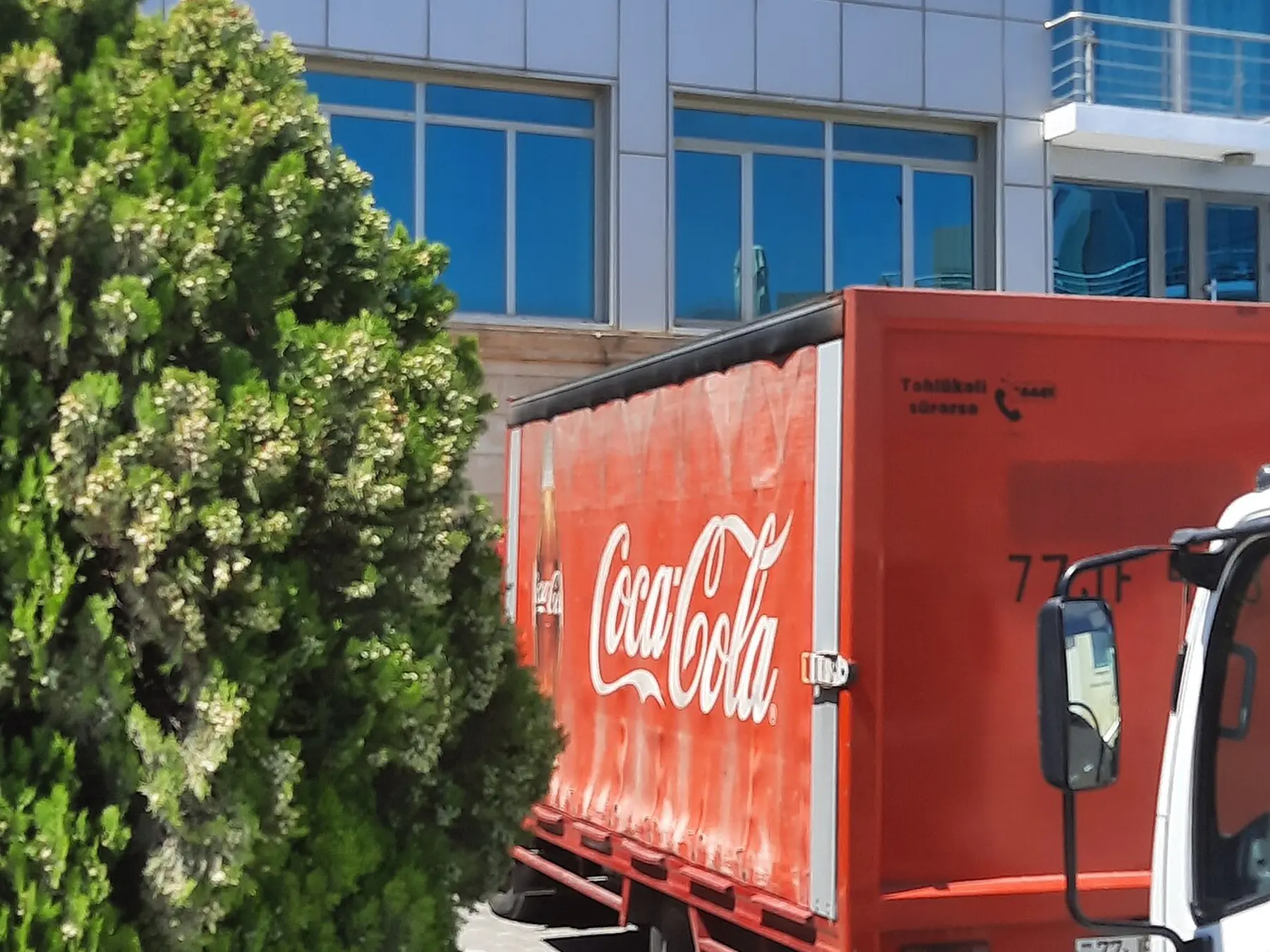 Red Coca-Cola delivery truck parked beside a building