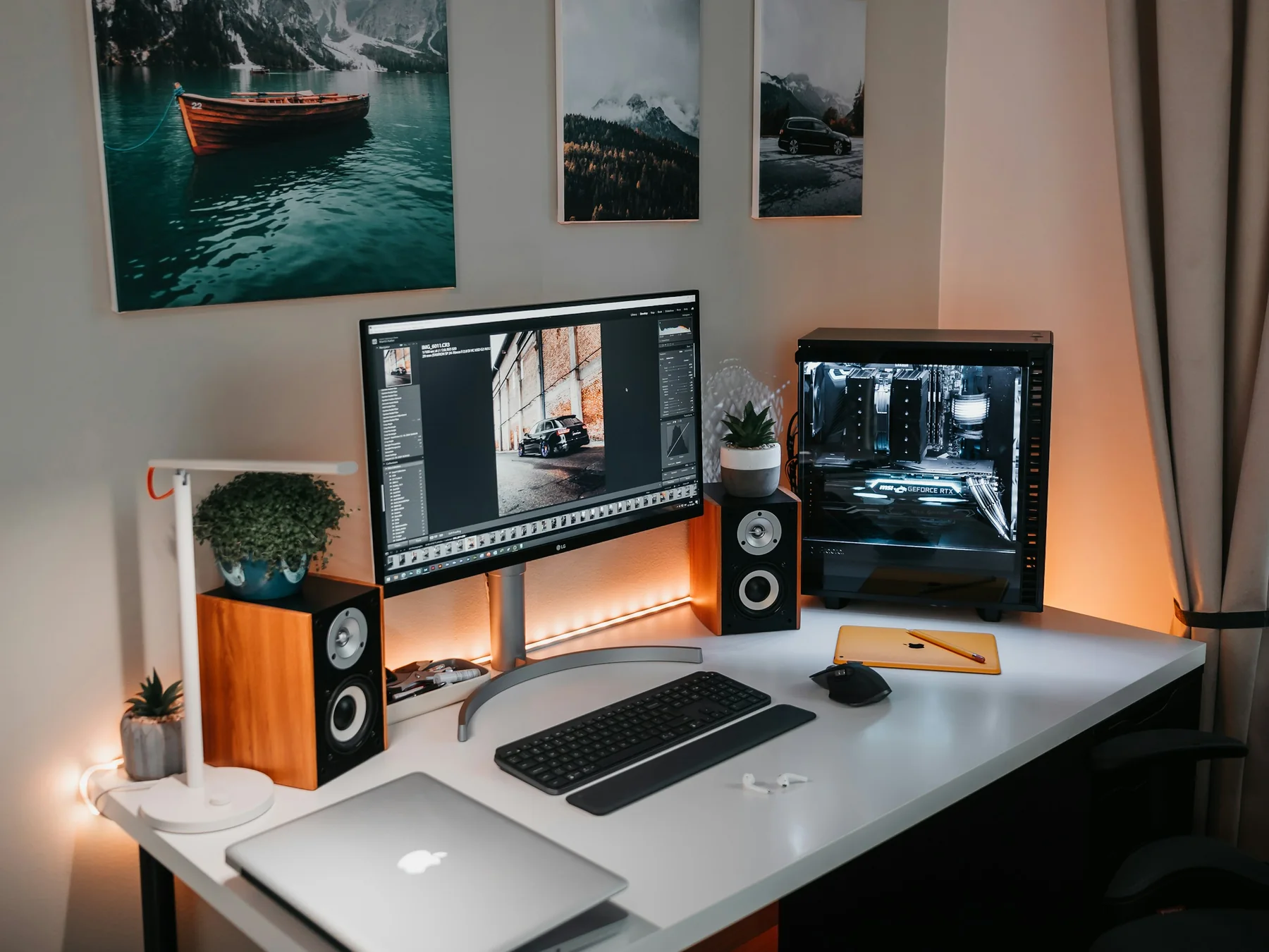Modern desktop computer with a large monitor, keyboard, speakers, and illuminated tower