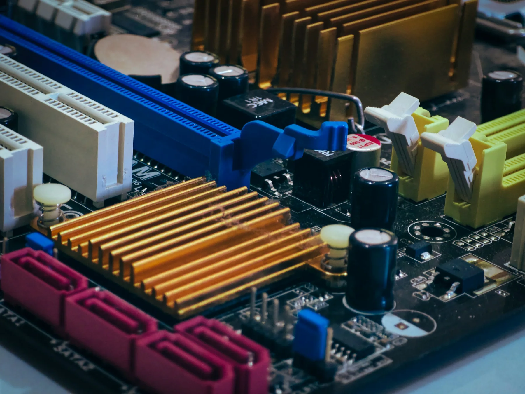 Close-up of a computer motherboard with heatsinks, capacitors, and expansion slots