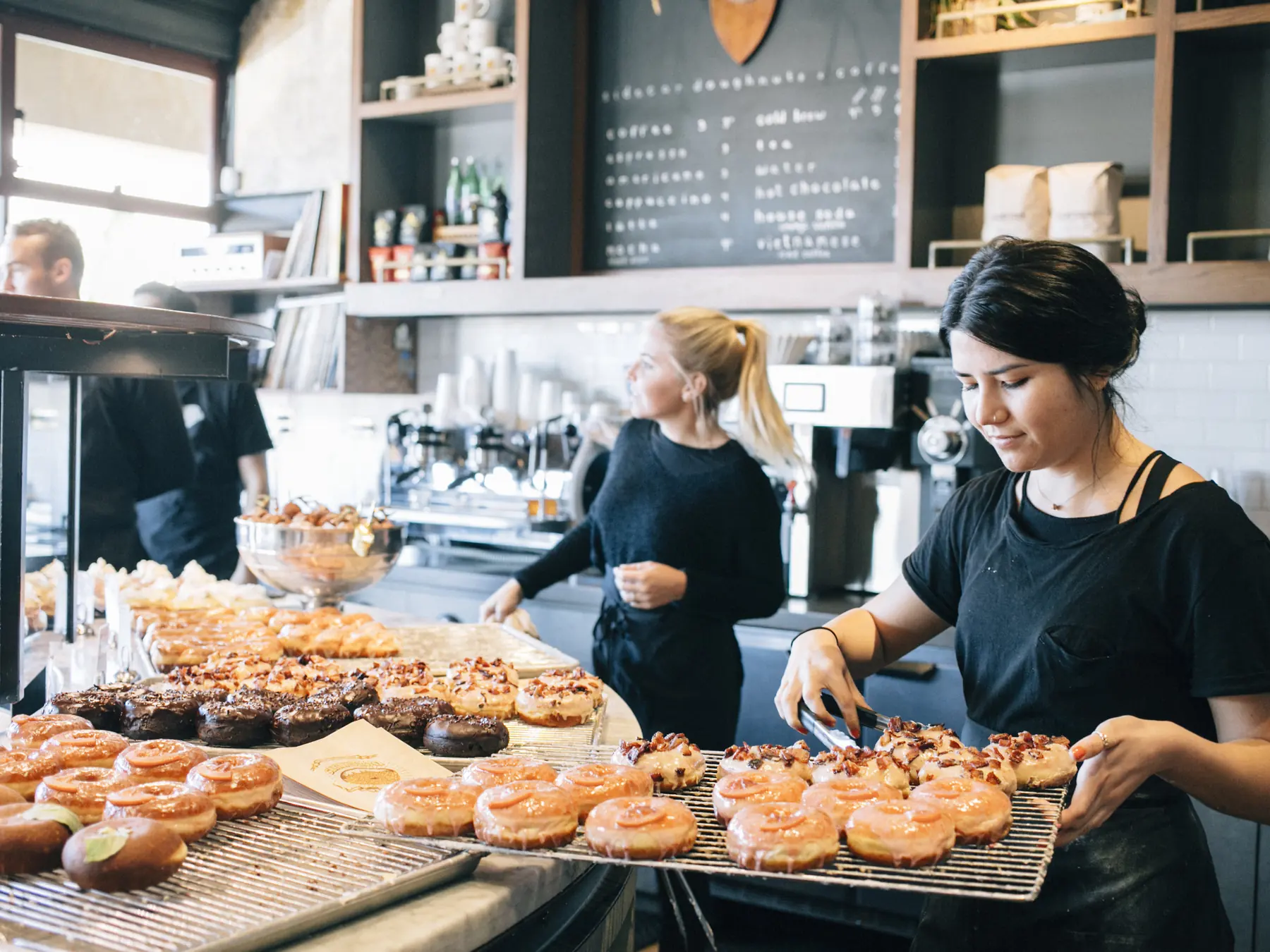 Bakery workers arranging freshly glazed doughnuts
