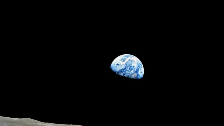 Earth rising above the Moon with sunlight illuminating the horizon