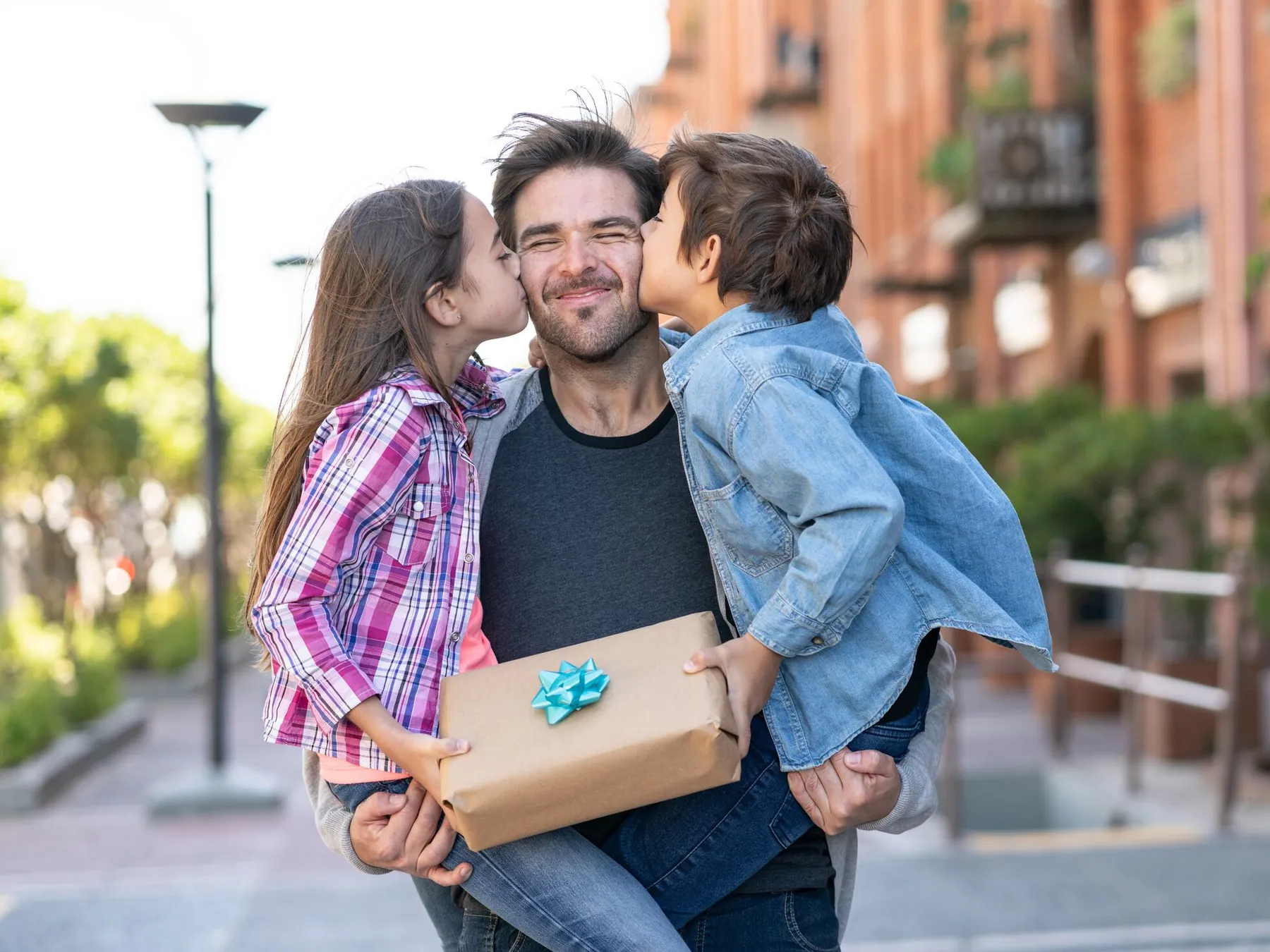 Father receiving a gift and kisses from his children