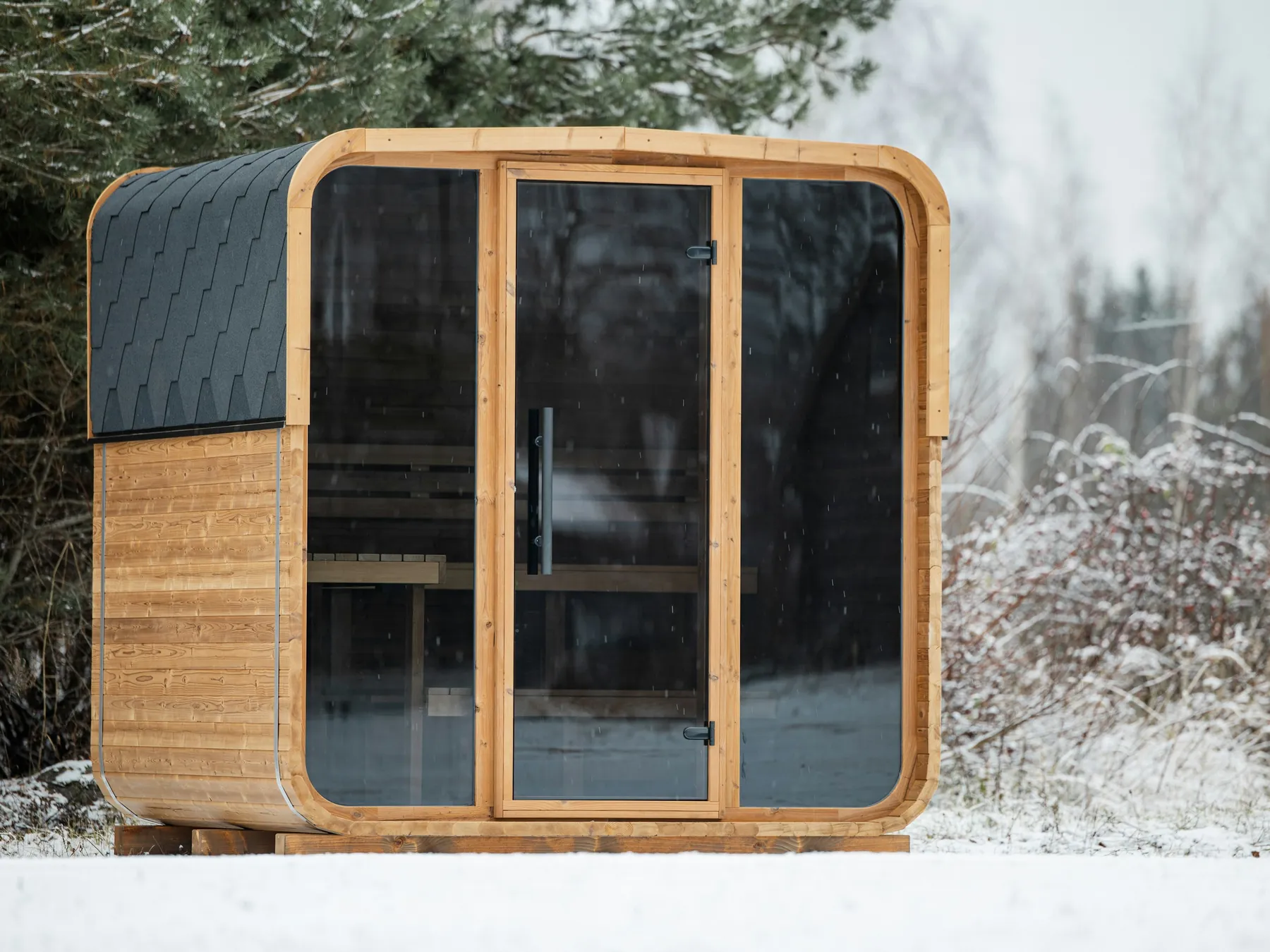 Modern wooden sauna cabin in a snowy forest landscape