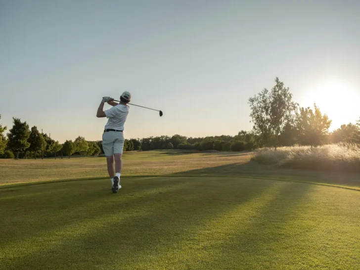 Golfer taking a swing on a sunlit course
