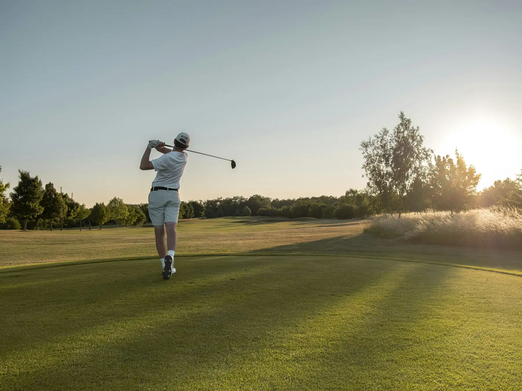 Golfer taking a swing on a sunlit course