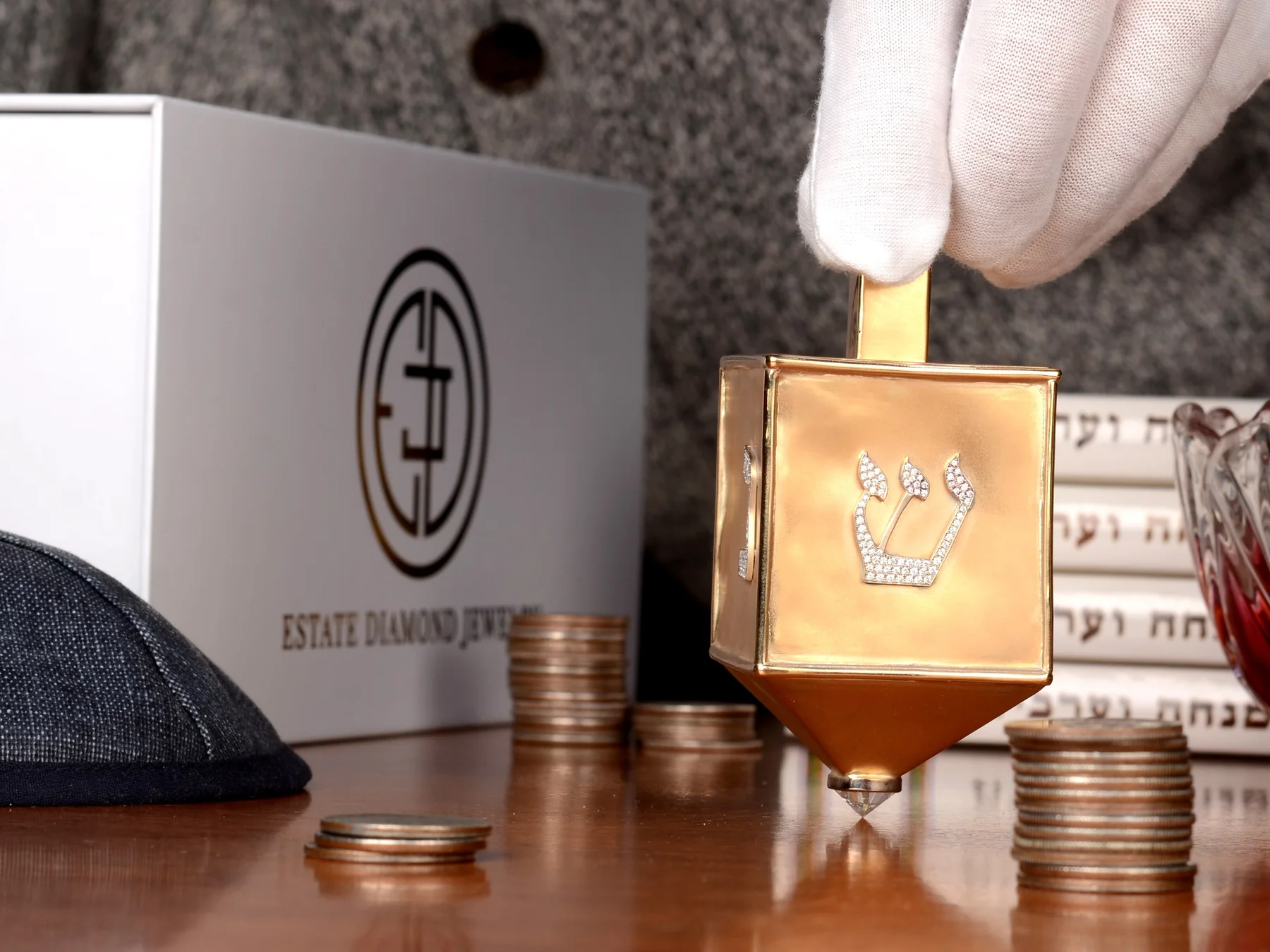 Gold Hanukkah dreidel beside stacks of coins and a dreidel box
