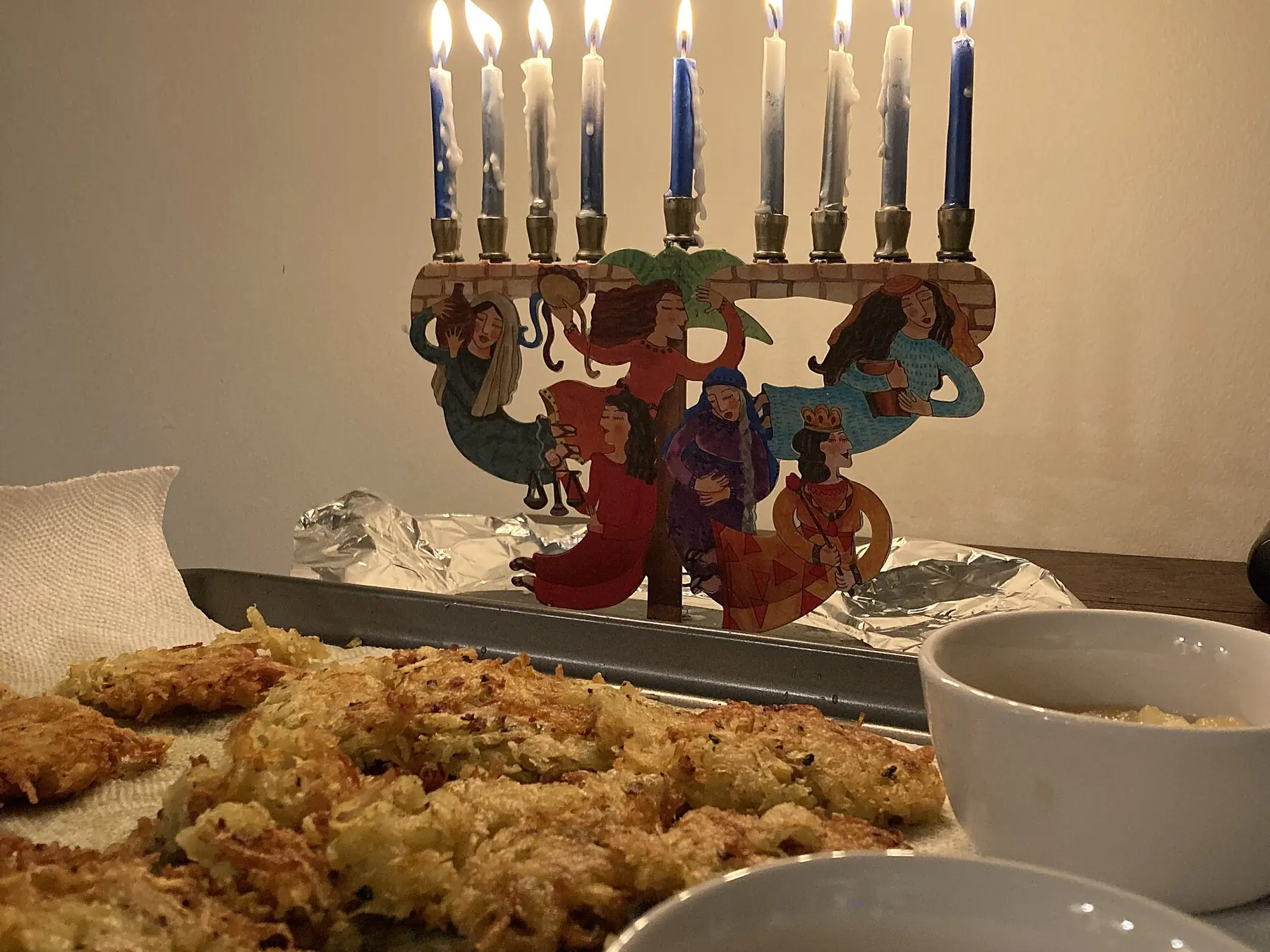 Lit Hanukkah menorah displayed beside a family holiday meal