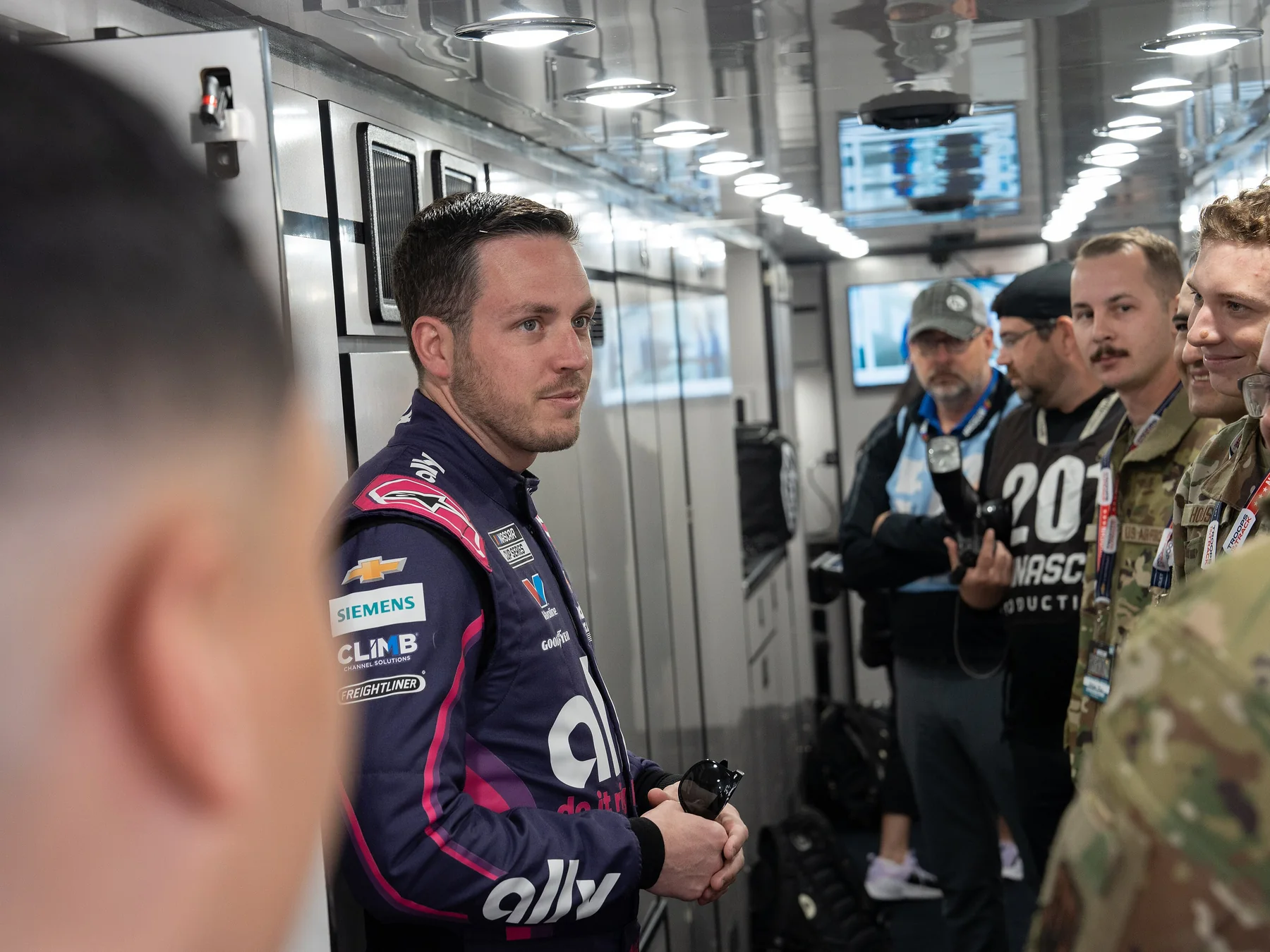 NASCAR driver speaking with people at a racetrack