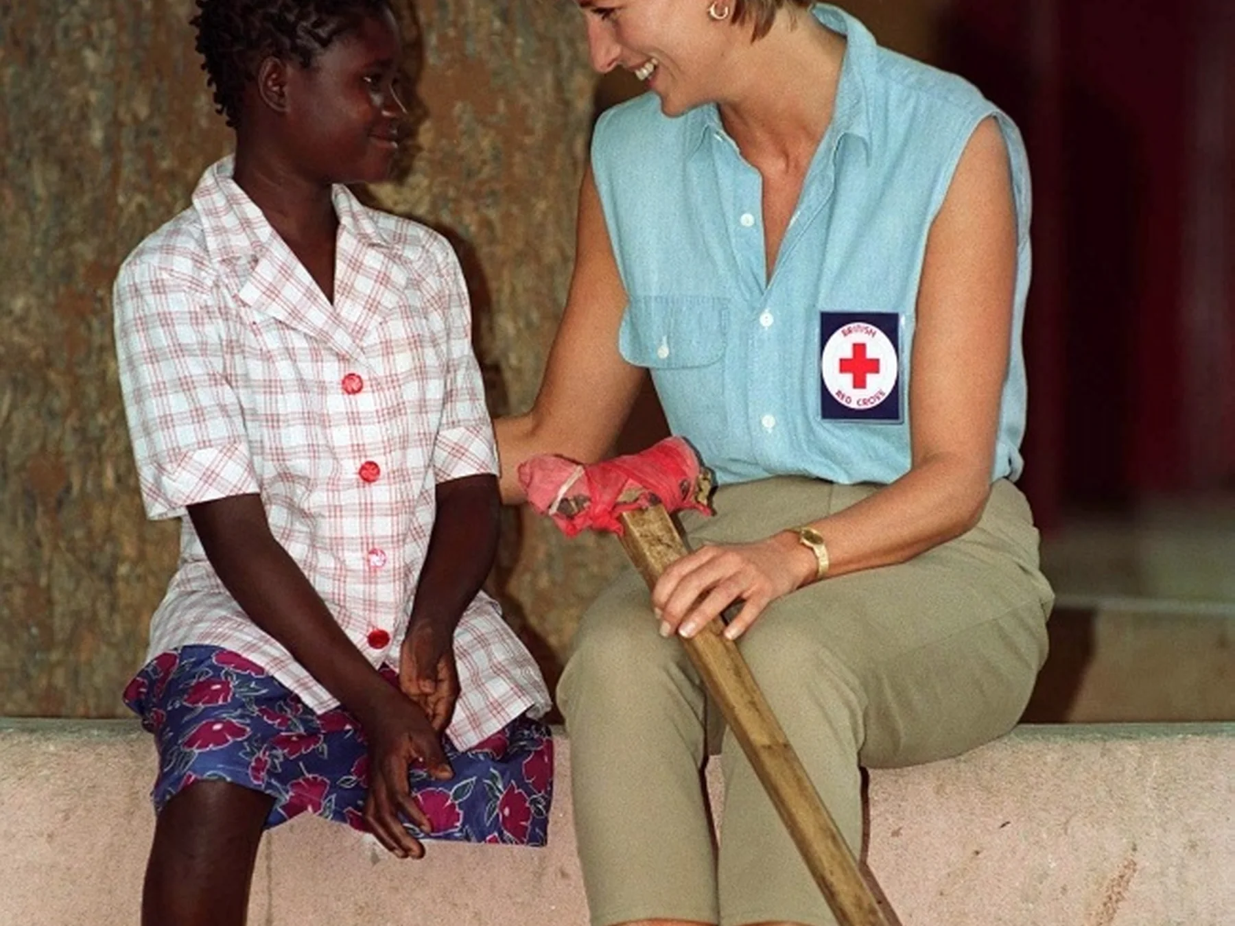 Princess Diana wearing a Red Cross vest while speaking with a woman