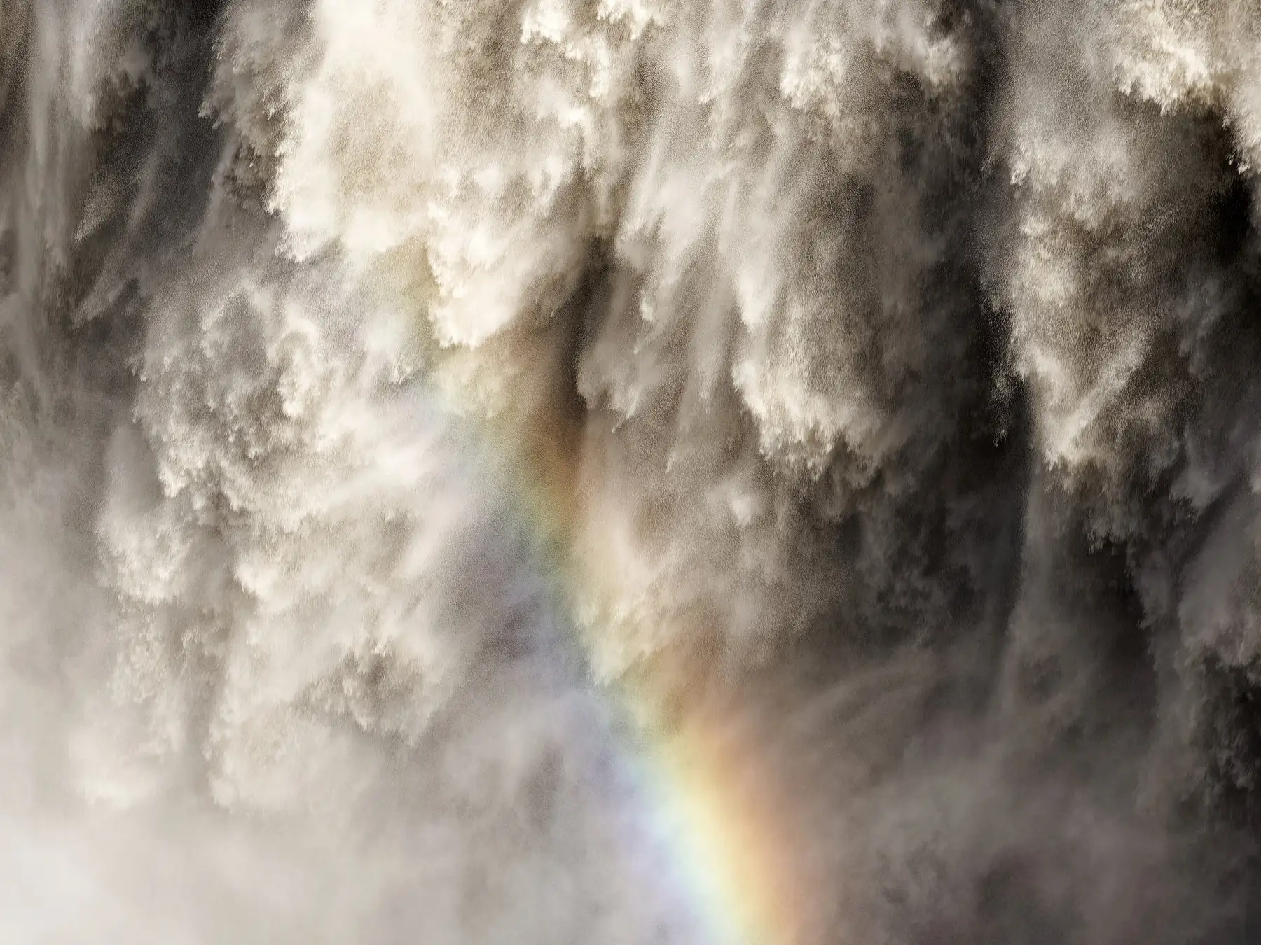Rainbow formed in the mist beside a waterfall