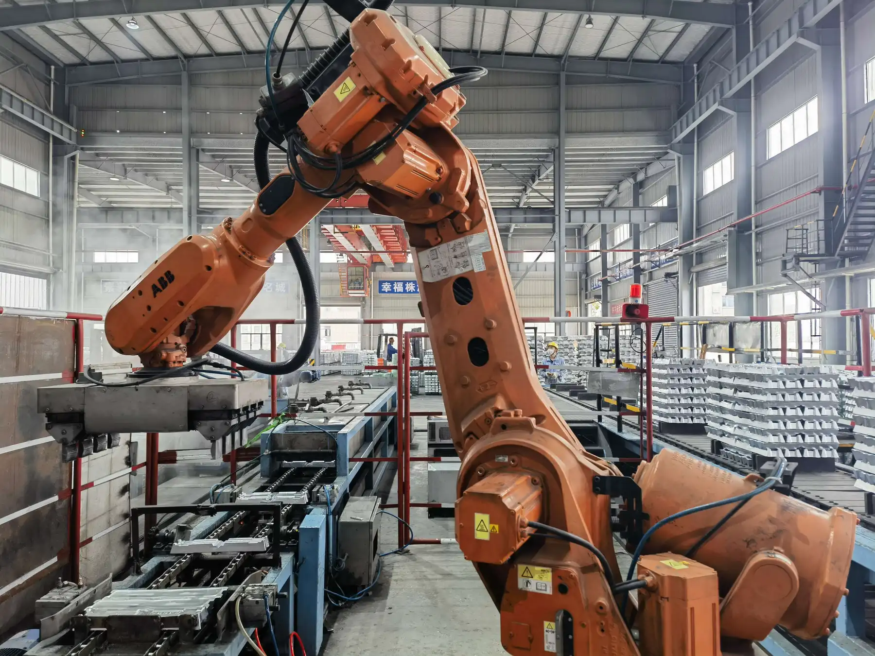 Large orange industrial robotic arm operating on a factory production line