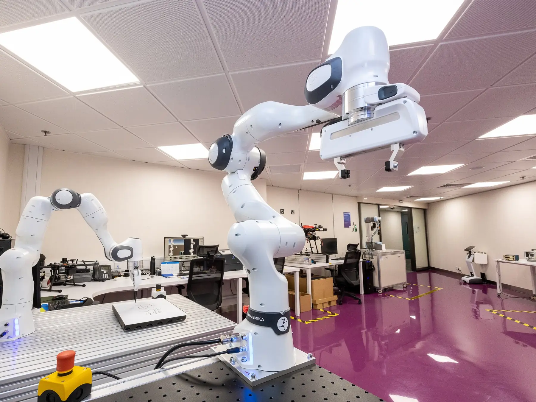 White robotic arms arranged inside a modern robotics laboratory