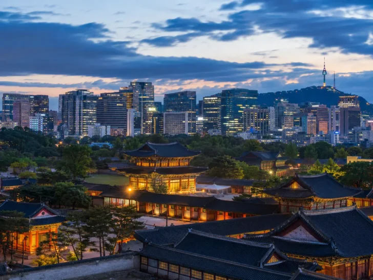 Seoul skyline at dusk with traditional Korean architecture in the foreground