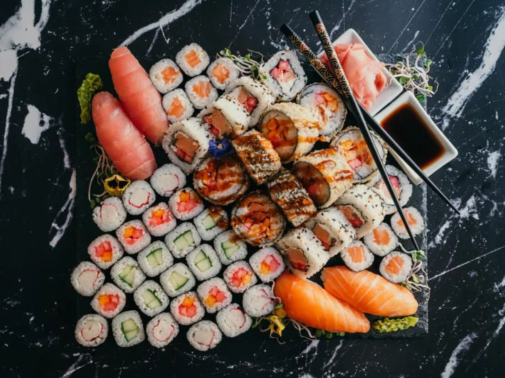 Large platter of maki rolls and nigiri sushi with chopsticks and soy sauce
