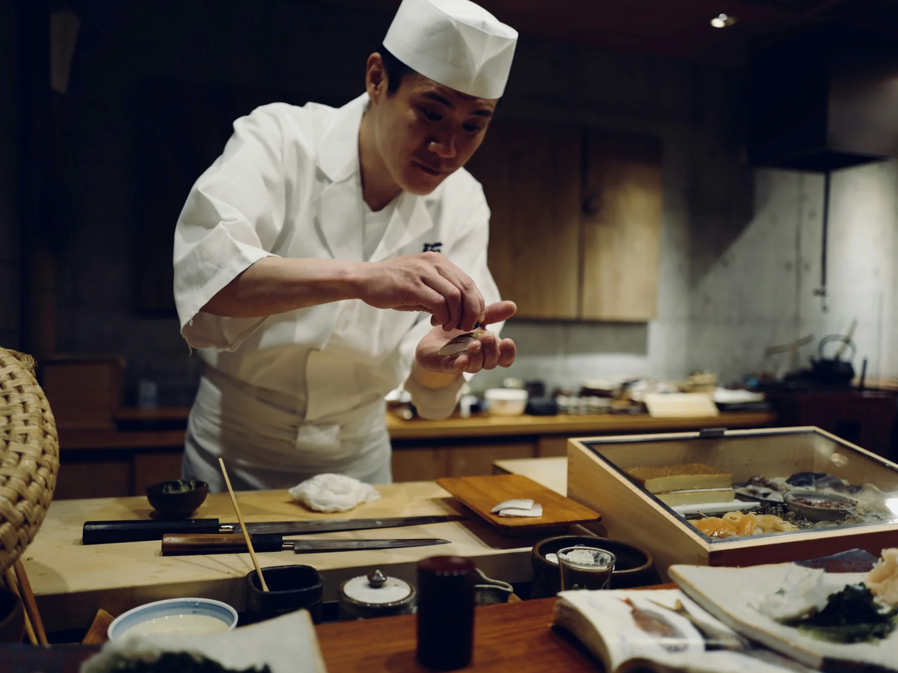 Sushi chef carefully shaping a piece of nigiri behind a restaurant counter