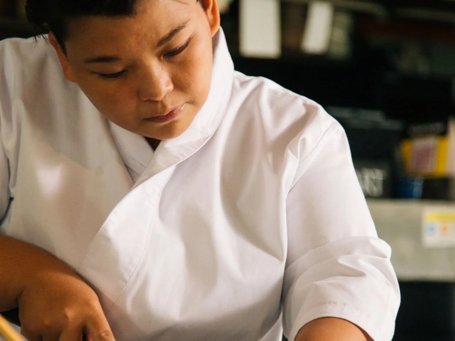 Sushi chef slicing and preparing a freshly made sushi roll