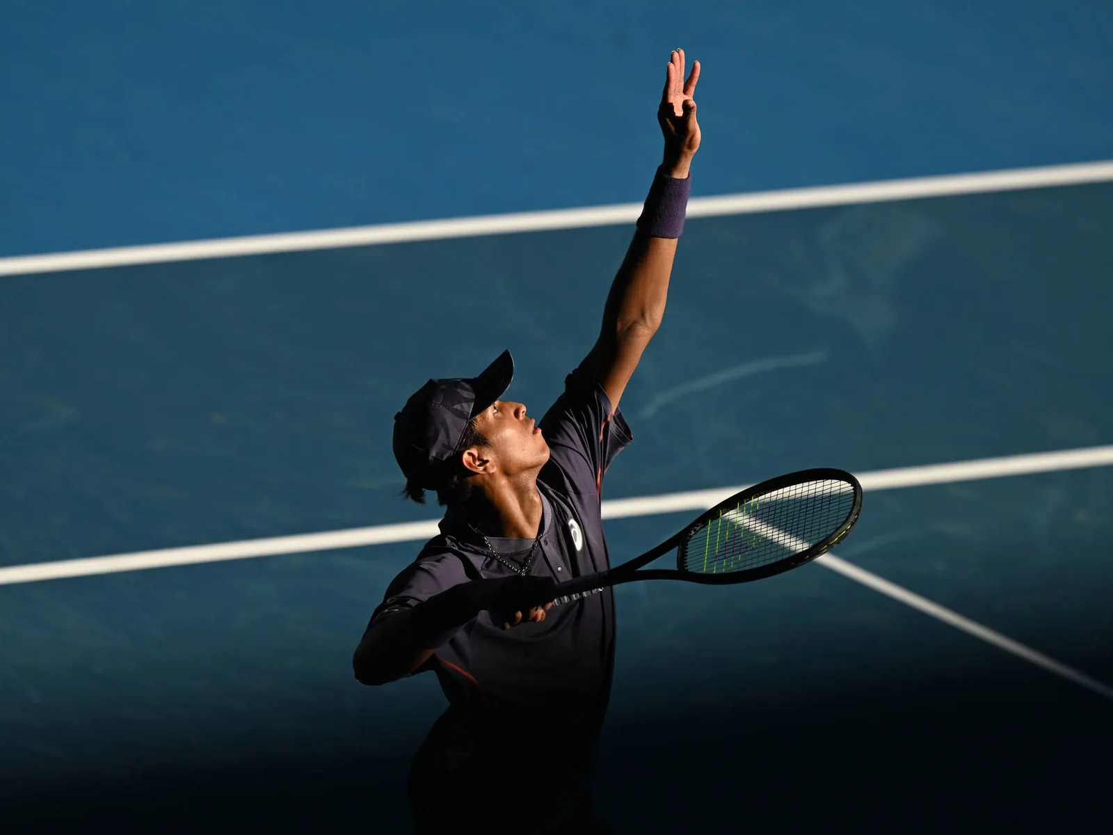 Tennis player serving on a hard court