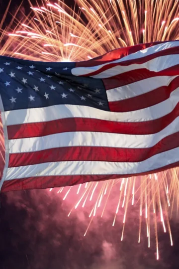 American flag waving in front of Fourth of July fireworks