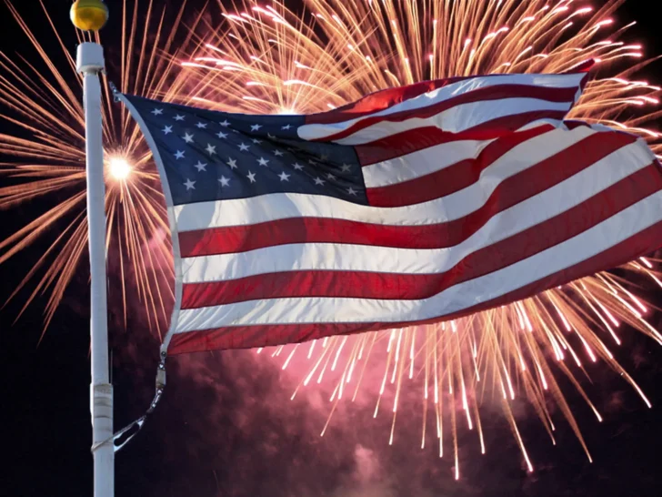 American flag waving in front of Fourth of July fireworks