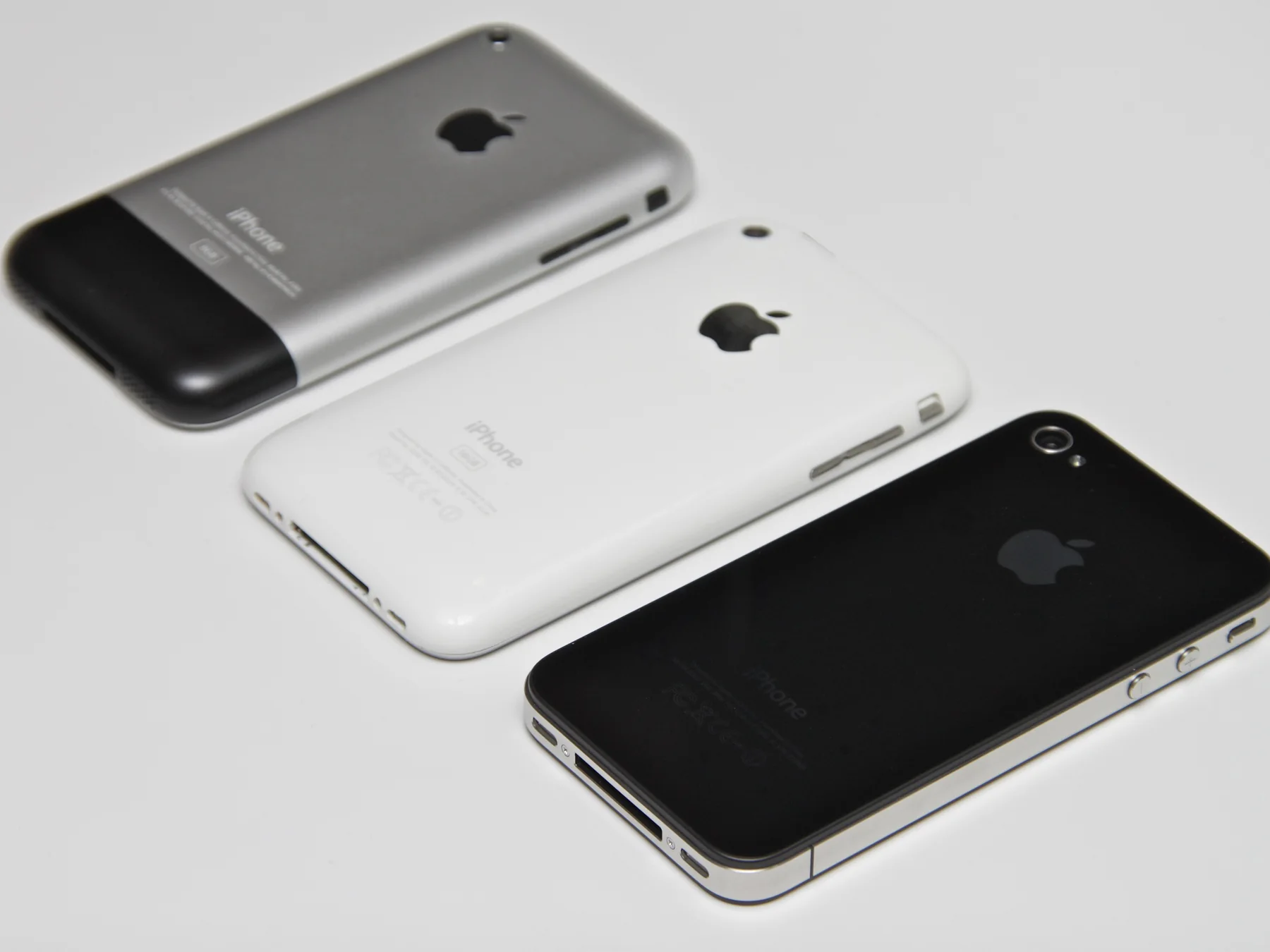 Three early Apple iPhone models shown from the back