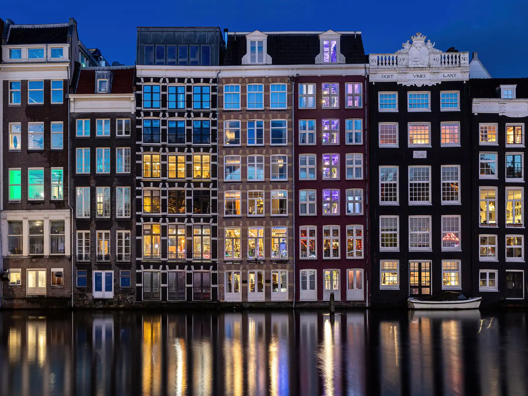 Narrow canal houses reflected in the water in Amsterdam