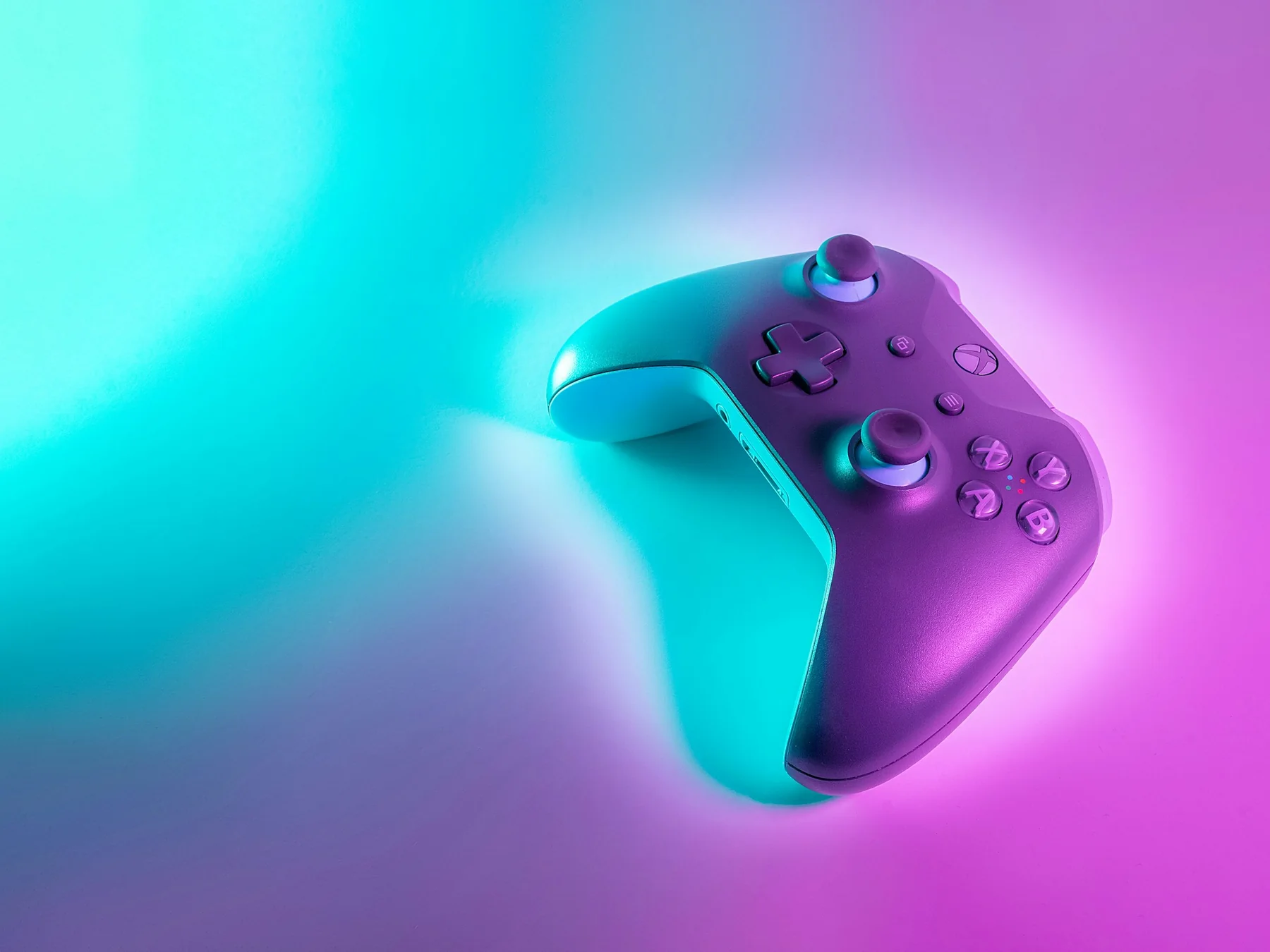 Video game controller lit by blue and magenta neon light