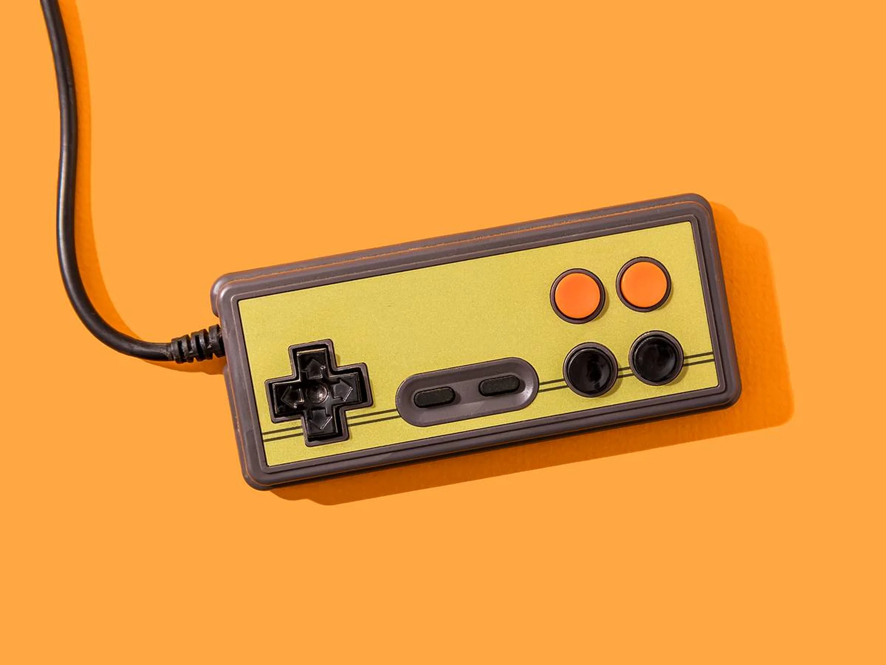 Vintage wired video game controller on an orange background