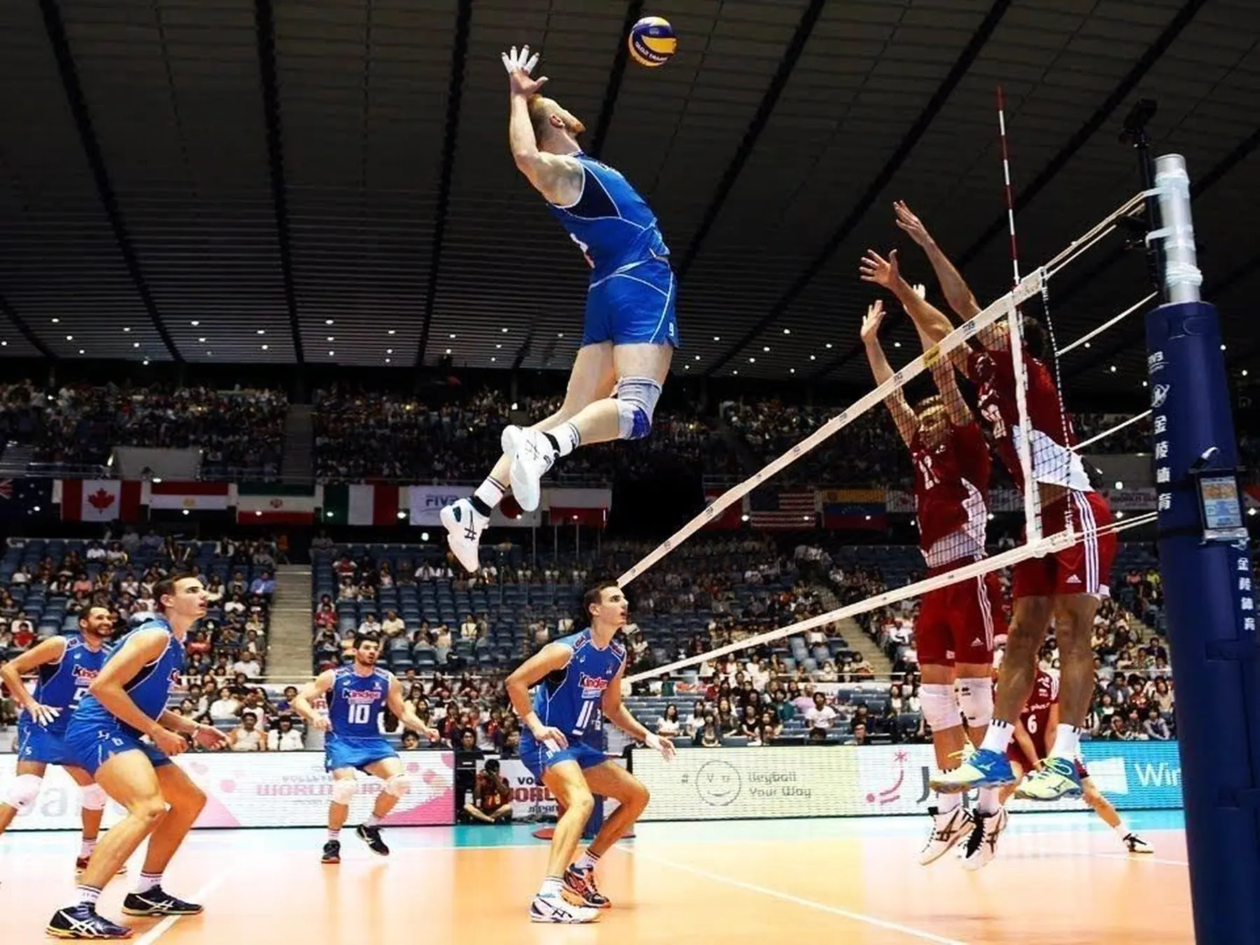 Volleyball player spiking the ball over the net