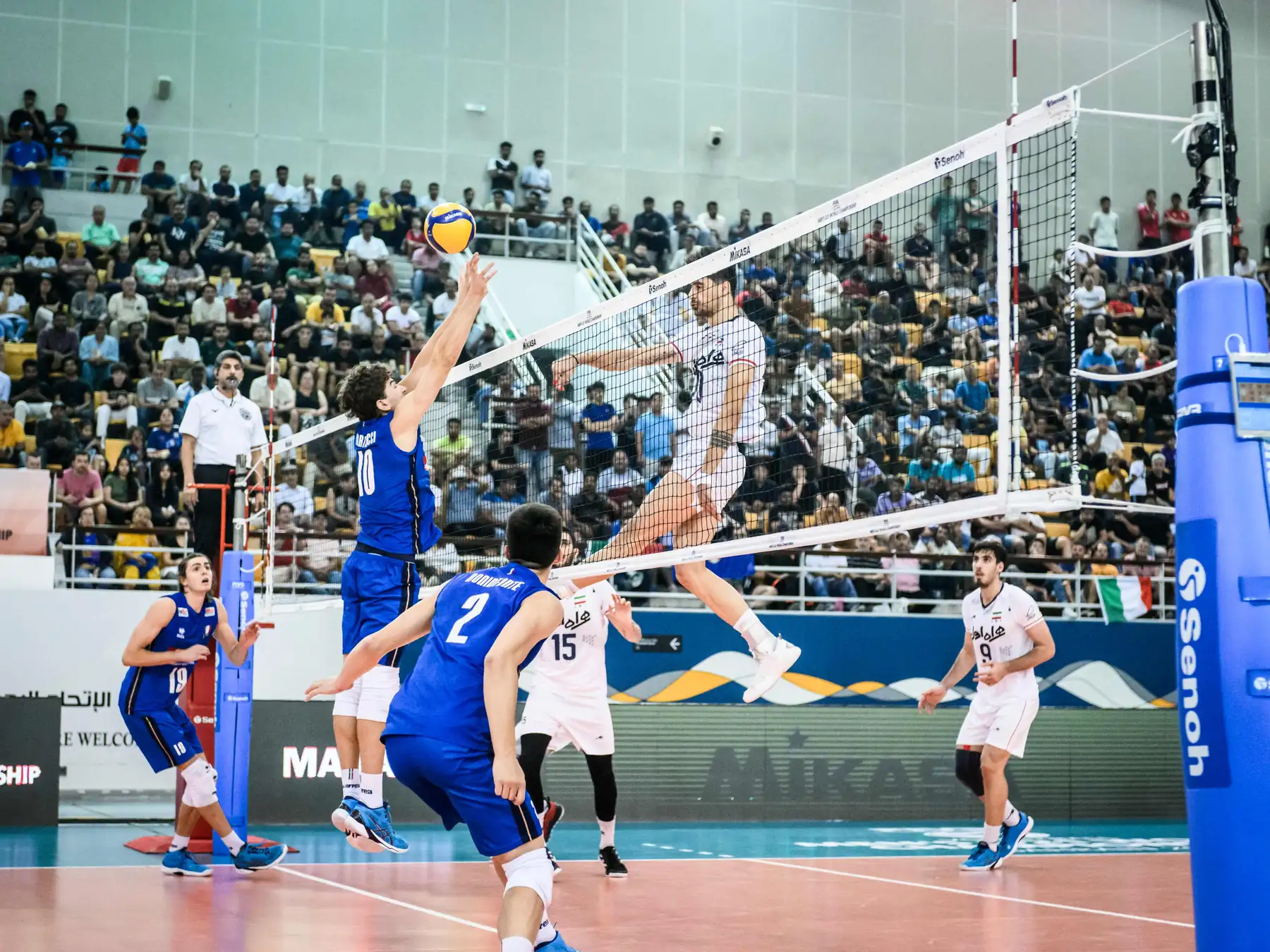 Volleyball players contesting the ball at the net