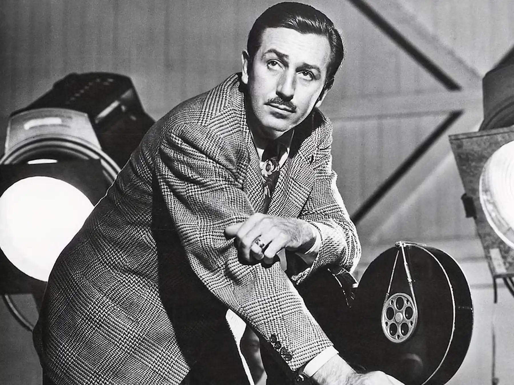 Walt Disney seated beside motion-picture film reels