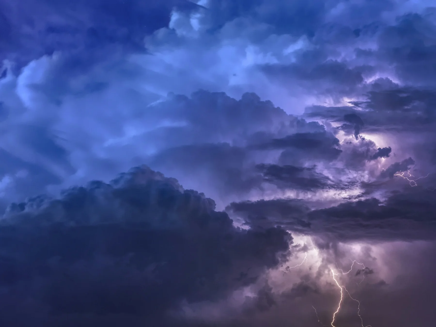 Lightning glowing inside dramatic blue and purple storm clouds