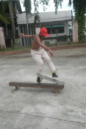 Skateboarder performing a trick over a low rail