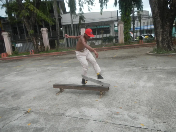 Skateboarder performing a trick over a low rail