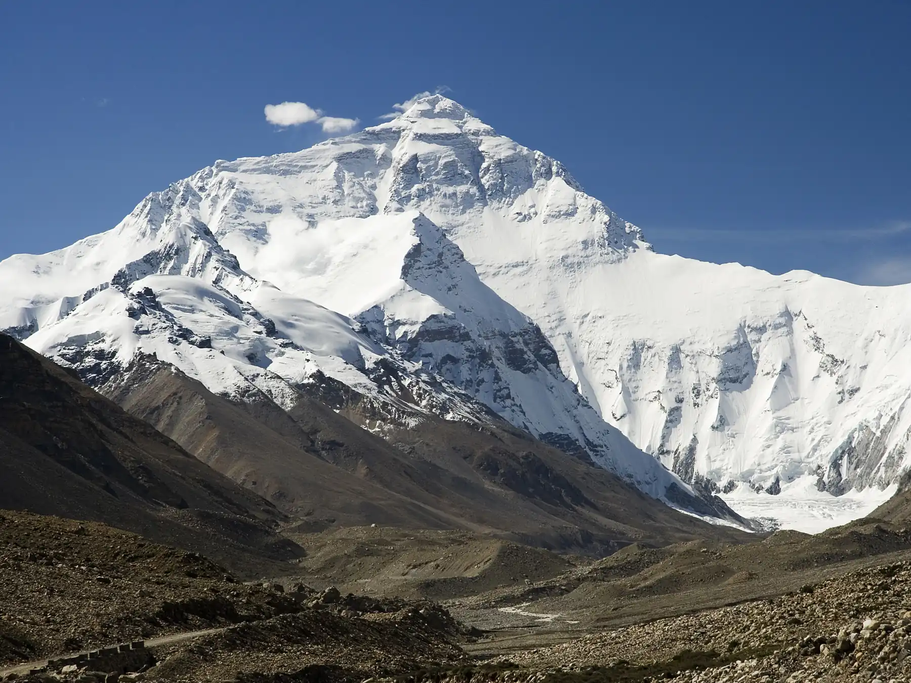 Snow-covered Mount Everest seen from a rocky plateau