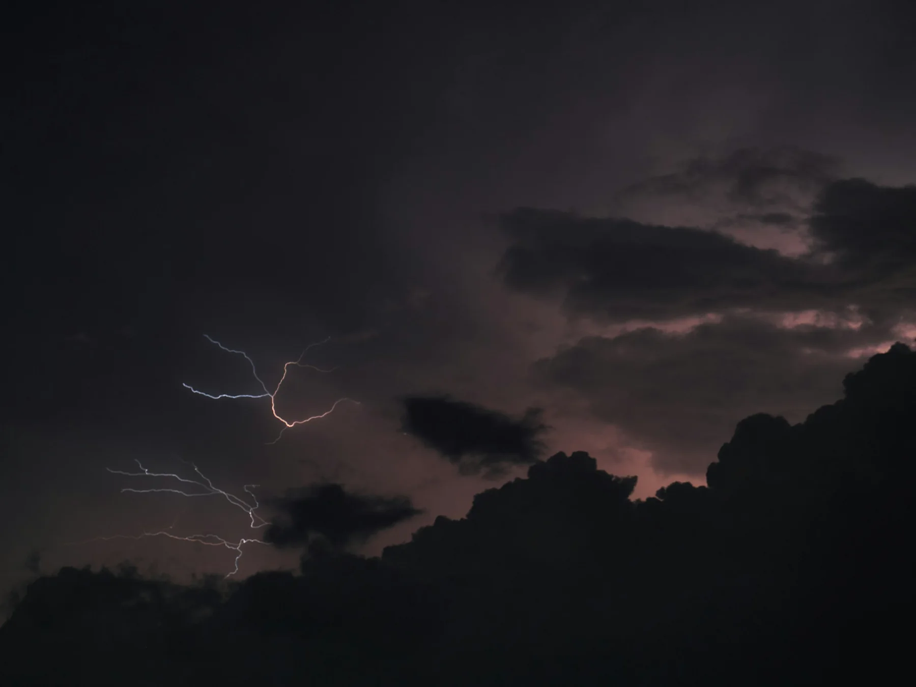 Lightning flashing beneath dark thunderstorm clouds