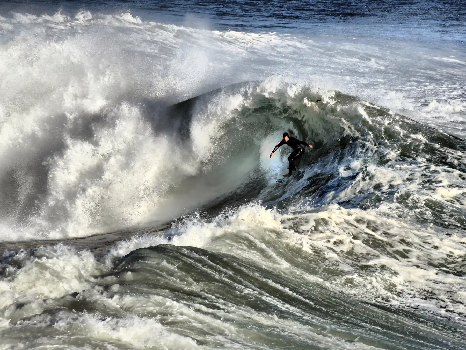 Surfer carving across a large breaking wave