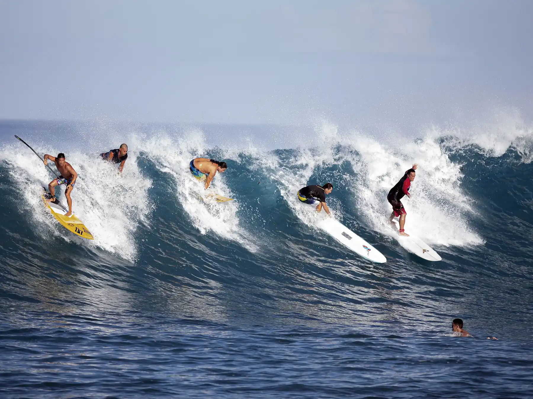 Several surfers riding the same ocean wave