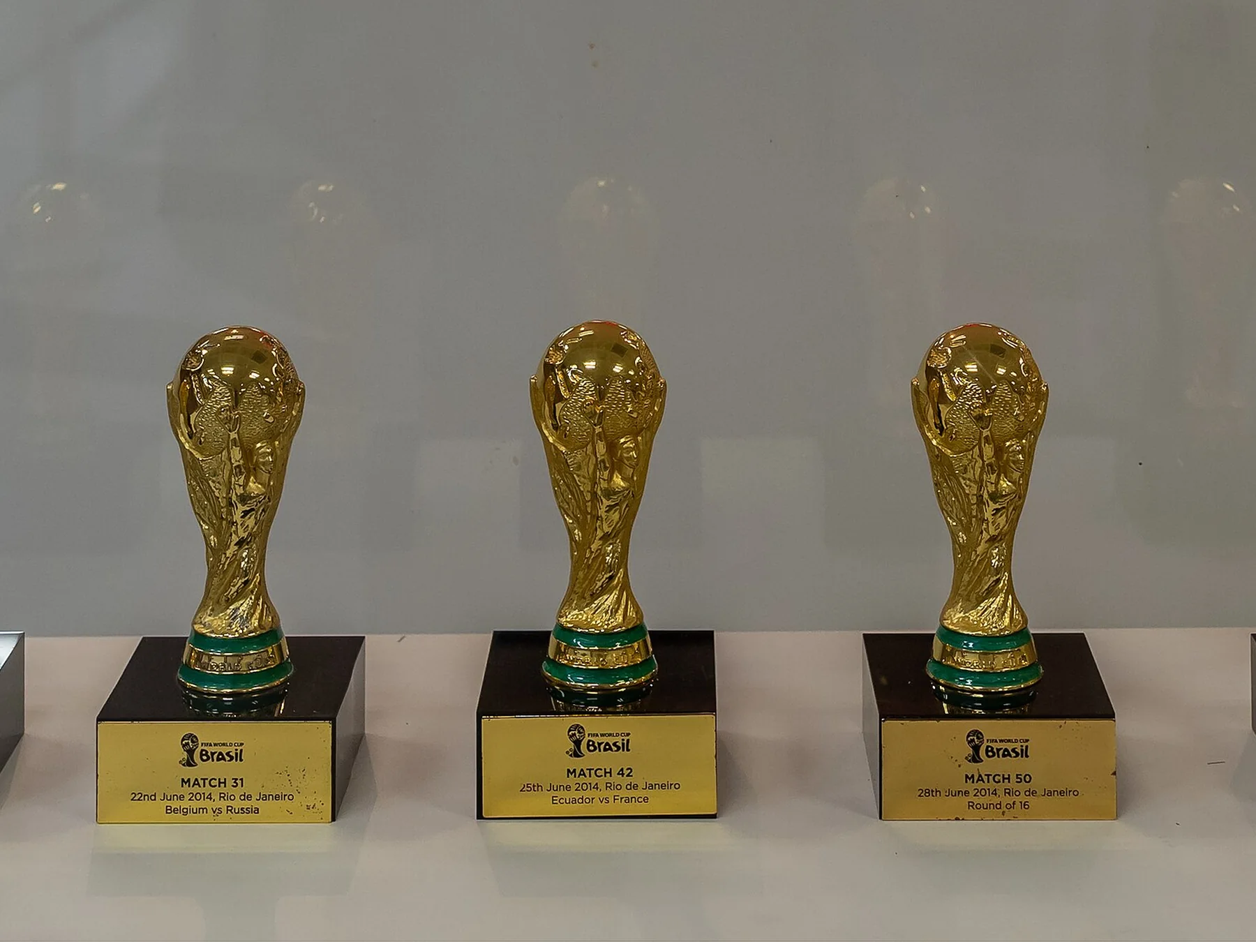 Three golden World Cup trophy replicas on display