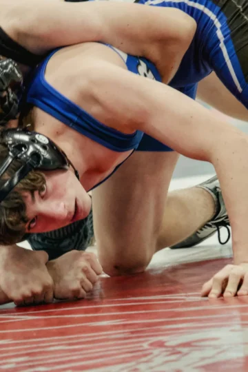 Wrestlers grappling on a red mat