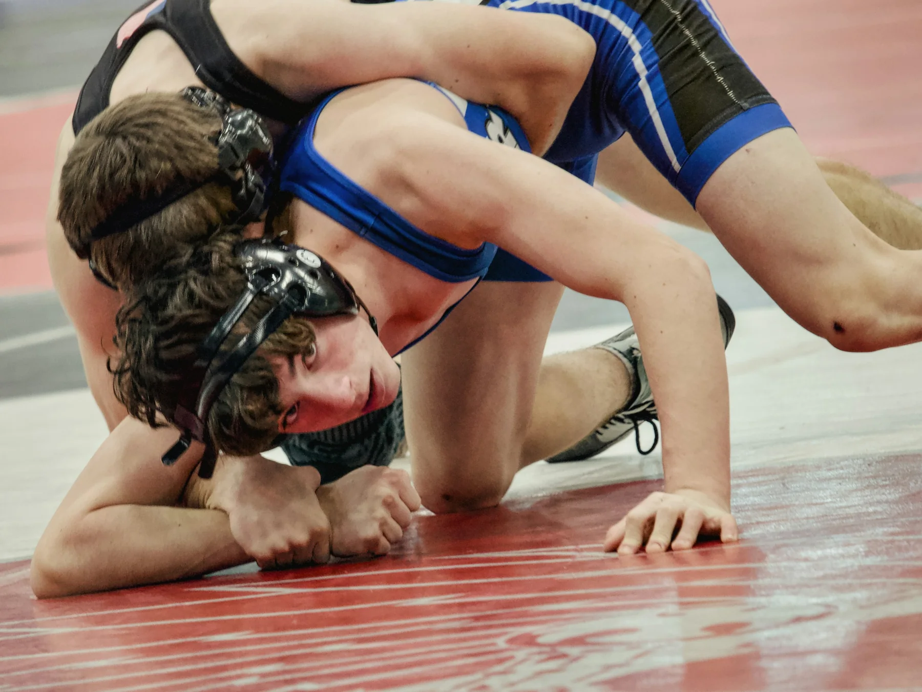 Wrestlers grappling on a red mat